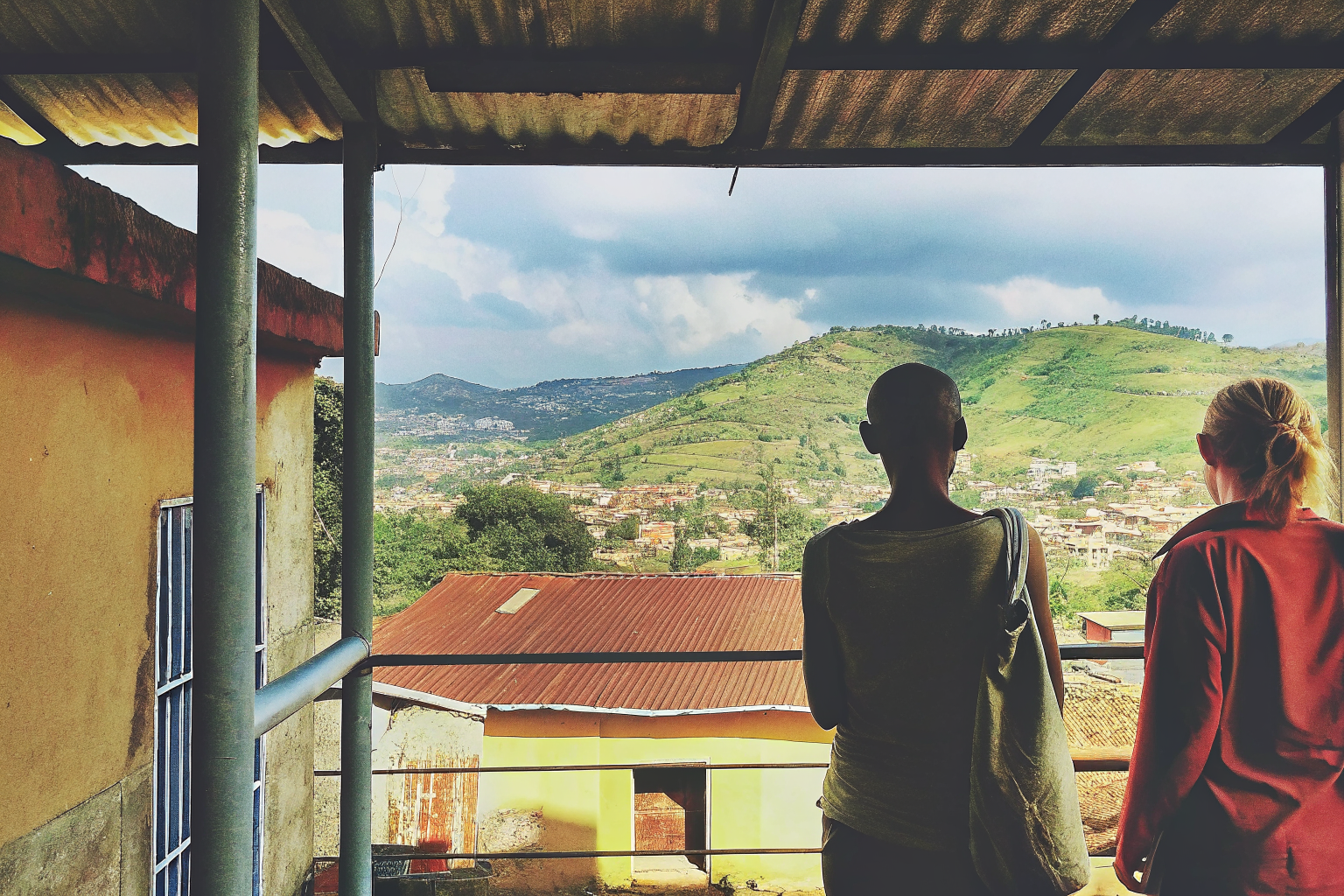 Two travellers looking out over the hills of Kampala at golden hour